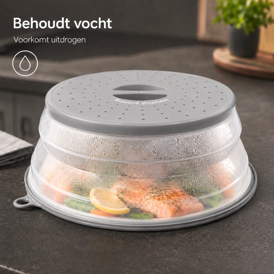 Grijs, inklapbaar magnetrondeksel met stoomopeningen, dat een bord met zalm en broccoli bedekt, met condens op de deksel.