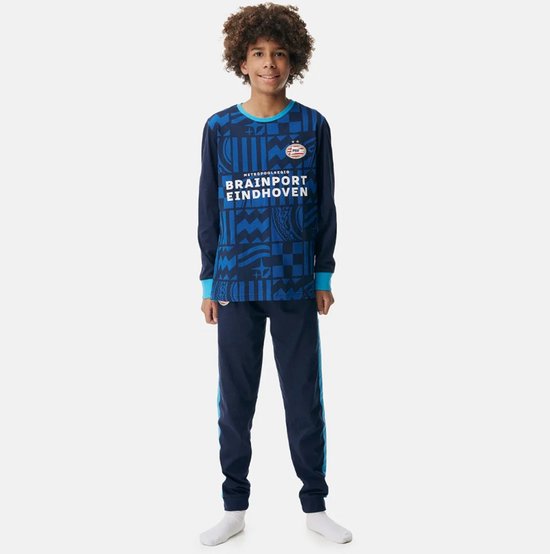 Jongen in een PSV pyjama. De pyjama is blauw met een geometrisch patroon en de tekst 'METROPOOLREGIO BRAINPORT EINDHOVEN'.