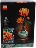 Chrysanthème Lego dans un vase vert avec une bande dorée et un socle marron. Les fleurs sont orange et rouges.