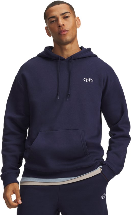 Model draagt een marineblauwe Under Armour hoodie met capuchon en wit logo, gecombineerd met bijpassende broek.