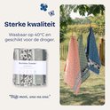 Trois torchons pliés avec des motifs floraux, de vaches et d'étoiles sur la corde à linge.
