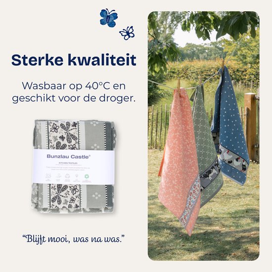 Trois torchons pliés avec des motifs floraux, de vaches et d'étoiles sur la corde à linge.