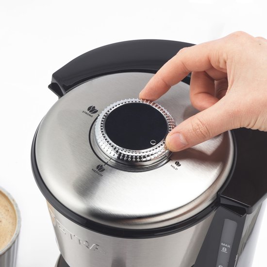 Hand draait aan zilverkleurige draaiknop van koffiezetapparaat: STRONG, MEDIUM, MILD.