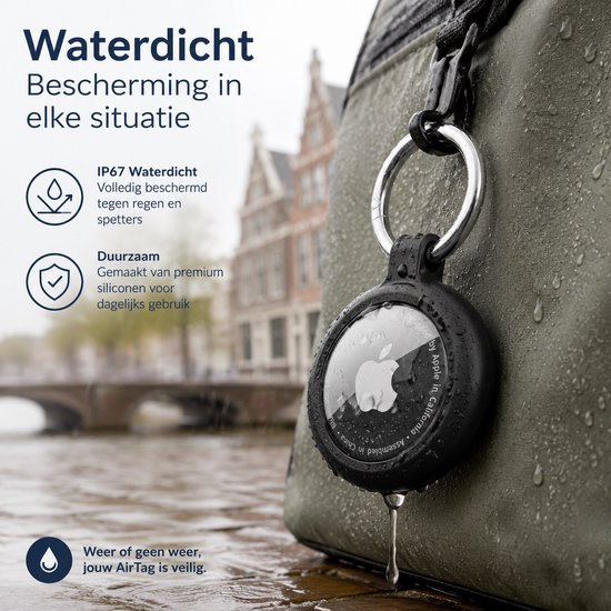 Zwarte AirTag-sleutelhanger aan een tas, druipend van de regen, met grachtenpanden op de achtergrond.