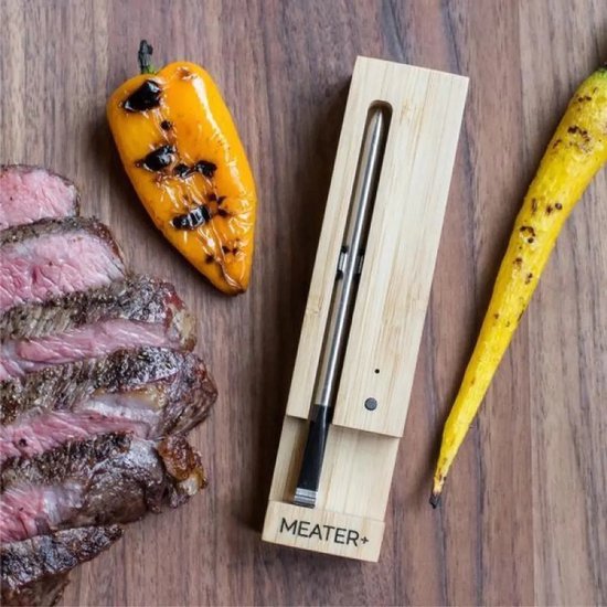 Meater+ thermometer in houten houder naast gegrilde paprika en steak.