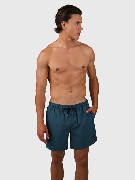 Homme portant un short de bain bleu-vert, avec cordon noir et logo sur la jambe gauche.