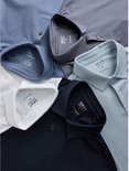 Bovenaanzicht van vijf opgevouwen poloshirts in diverse kleuren met Next-labels.