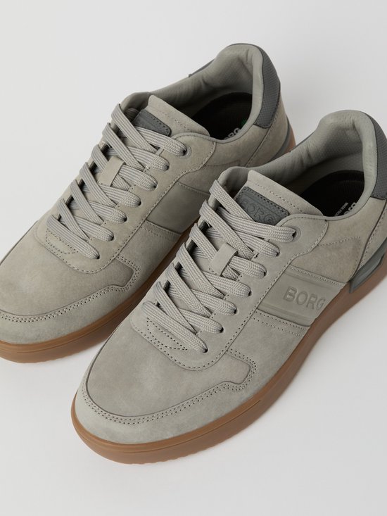 Close-up van grijze suède Björn Borg sneakers met bruine zool en veters.