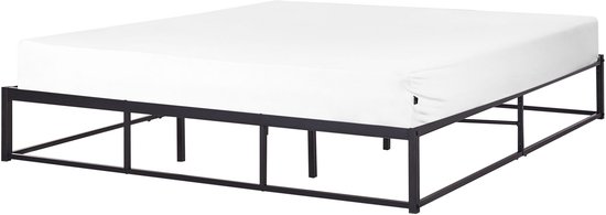 Cadre de lit en métal noir avec matelas et draps blancs, vu de côté.