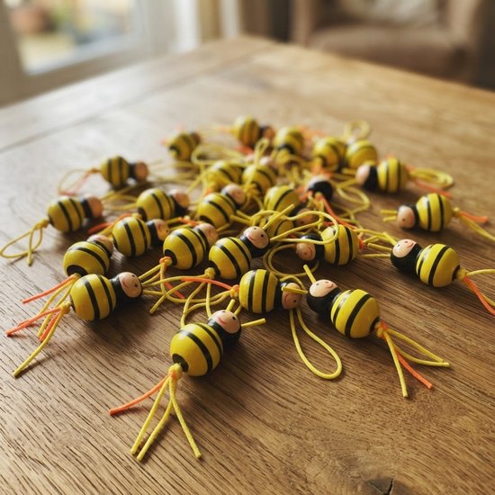 Een hoopje houten bijtjes met zwarte en gele strepen verspreid op een houten tafel.