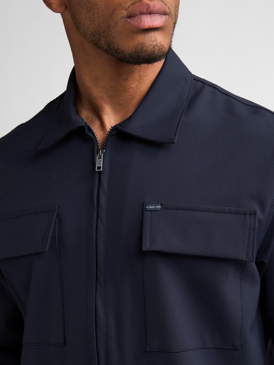 Detailopname van donkerblauw jack met ritssluiting, opstaande kraag en twee borstzakken.