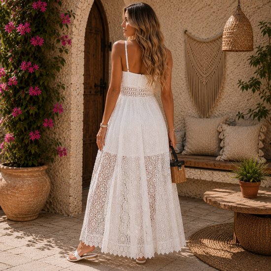 Combinaison-robe blanche en dentelle avec col en V, devant ouvert et ceinture smockée. Le mannequin porte des sandales blanches.