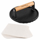 Gietijzeren hamburgerpers met houten handvat en een stapel bakpapier, op een witte achtergrond.