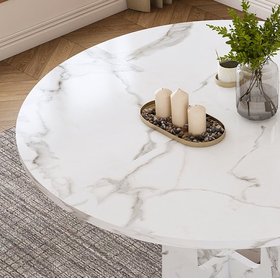 Ronde marmerlook eettafel met decoratieve kaarsen en een vaas met groen.