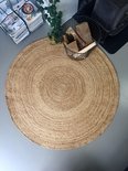 Rond jute vloerkleed met spiraalpatroon in een modern interieur met houtstapel.