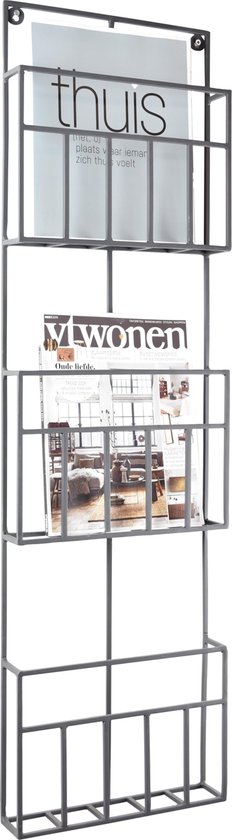Zwart metalen wandrek met drie vakken, gevuld met tijdschriften.
