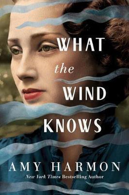 Boek kaft "What the Wind Knows" met een close-up van een vrouw met bruin haar, blauwe ogen en rode lippen. Watergolven over de afbeelding.