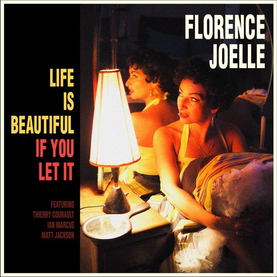 Florence Joelle en een spiegelbeeld zitten naast een lamp. Tekst: "Life Is Beautiful If You Let It".