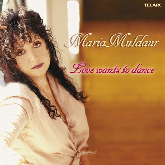 Album cover van Maria Muldaur 'Love Wants to Dance' met een portret van Maria Muldaur, die een beige blouse met knoopdetail draagt.