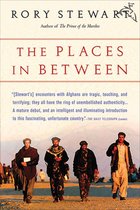 Boekomslag met de titel 'The Places In Between' van Rory Stewart. Vier mannen in traditionele kleding lopen op een zandpad.