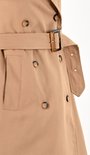 Sluiting van camelkleurige trenchcoat met bruine knopen en ceintuur.