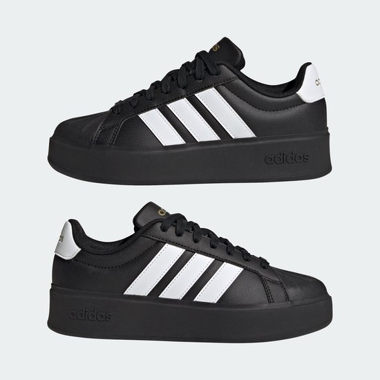 Twee zwarte damessneakers met dikke zolen, witte Adidas-strepen op de zijkant en gouden details.