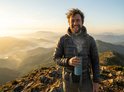 Man met blauwe drinkfles in de bergen bij zonsopgang.