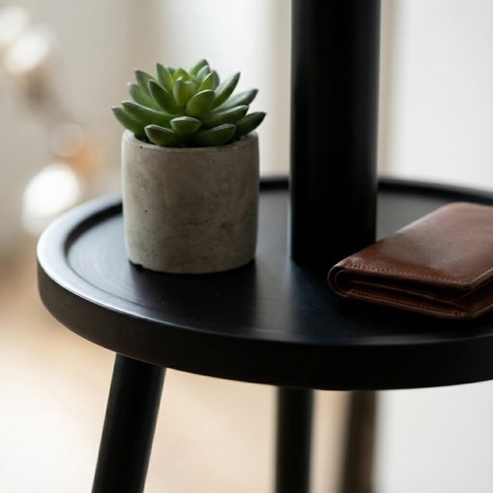 Detail van een zwart, rond tafeltje met een succulente plant in betonpot en een portemonnee.