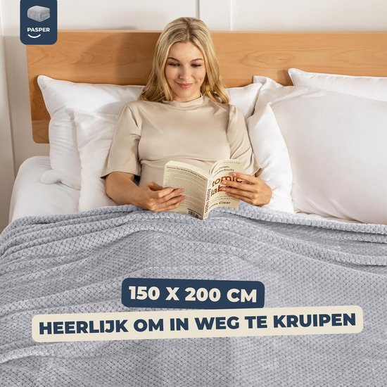 Vrouw leest een boek onder een grijze wafeldeken op bed. Afmeting 150 x 200 cm.