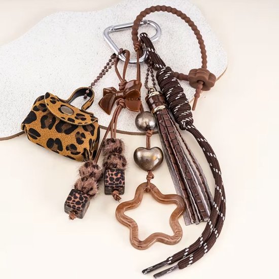 Sleutelhanger met luipaardprint tasje, bruine kwast, ster, hartvormige kralen, strik en touwdetail.