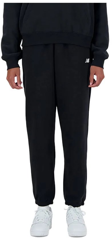 Zwarte New Balance joggingbroek met wit logo, gedragen met witte sneakers.
