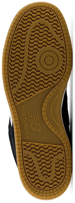 Onderkant van bruine rubberen zool van zwarte New Balance sneakers met visgraatprofiel.