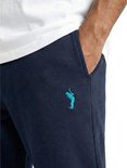 Detail van een navy joggingbroek met petrolblauw logo op de linkerheup.