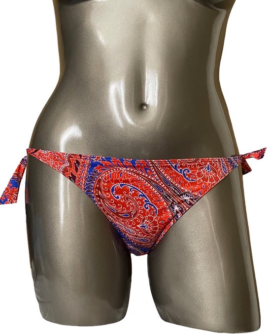 Rood, blauw en wit paisley bikinislip met strikjes aan de zijkanten, gedrapeerd op een grijze paspop.