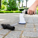 Vrouw giet blauwe vloeistof in witte schuimsproeier, met de opzetstuk ernaast op de grond.