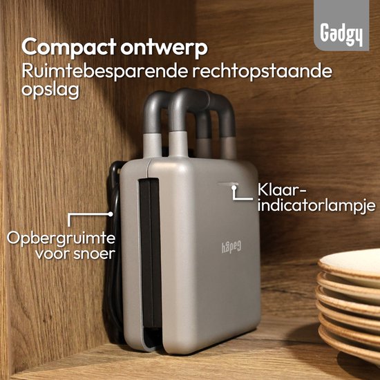 Grijze, gesloten wafelijzer met dubbele handgrepen, opgeborgen in een houten kast. Indicatorlampje is aan.