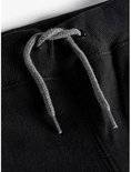 Grijze trekkerkoorden van een zwarte joggingbroek, met een knoop aan de binnenkant van de tailleband.