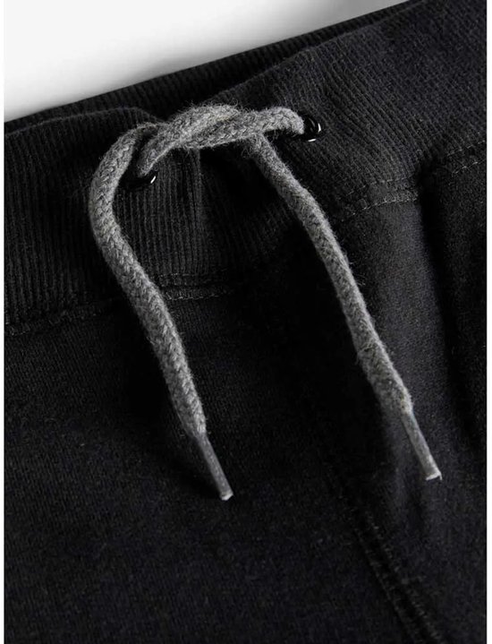 Grijze trekkerkoorden van een zwarte joggingbroek, met een knoop aan de binnenkant van de tailleband.