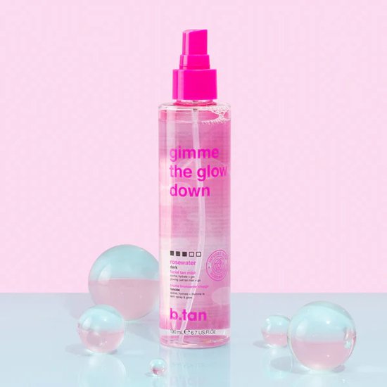 Roze fles met 'gimme the glow down' tekst, met pompje en vernevelaar. Omringd door transparante bolletjes.