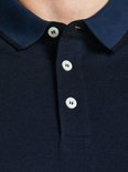 Close-up van een donkerblauw poloshirt met navy kraag en drie witte knopen.
