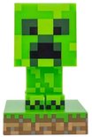 Een pixelachtige, felgroene Minecraft Creeper-lamp op een gras- en aarde-voetstuk.