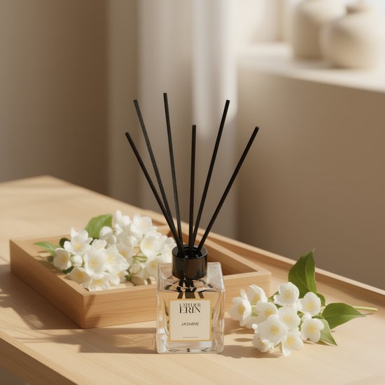 L'Atelier Erin Jasmijn reed diffuser met zwarte stokjes, omringd door verse jasmijnbloemen.