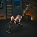 Man in grijs shirt doet een buikspieroefening op een zwarte fitnessbank.