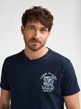 Man met donkerblauw T-shirt met een kleine grafische print op de borst.