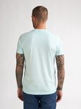 Man van achteren gezien in lichtgroen T-shirt en spijkerbroek.