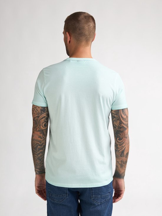 Man van achteren gezien in lichtgroen T-shirt en spijkerbroek.
