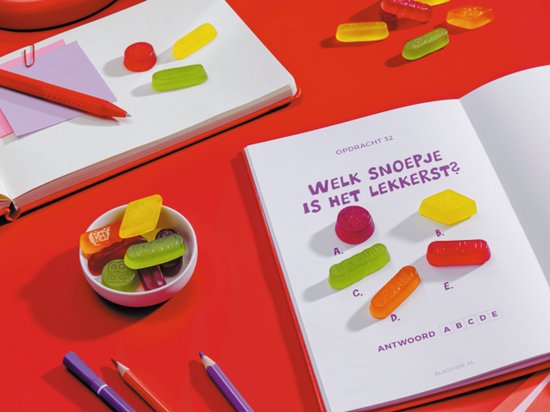 In een boek staan afbeeldingen van snoepjes. Een kommetje met rode, groene, paarse, gele en oranje snoepjes.