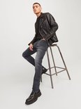 Detail van de achterzak van een grijze jeans en de rits van een leren jack.