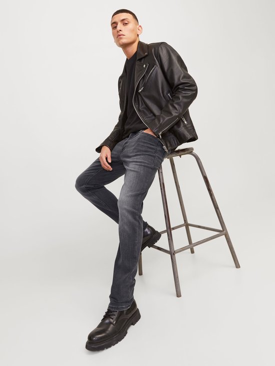 Detail van de achterzak van een grijze jeans en de rits van een leren jack.
