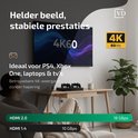 Zwarte HDMI kabel op een bureau met twee controllers, een kopje en een plant, voor 4K 60Hz gaming.